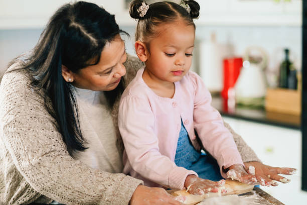 istock Grandmother, girl and cooking with rolling pin in kitchen, dough or learning with help at family house. Child, grandma and love for baking, teaching or guide with flour, development and food in home 2205496163