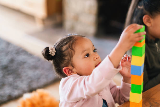 istock Playing, learning and kid with building blocks in home for development, fun and growth. Creativity, puzzle and girl child with geometric activity for skills and cognitive education with toys in house 2205496181