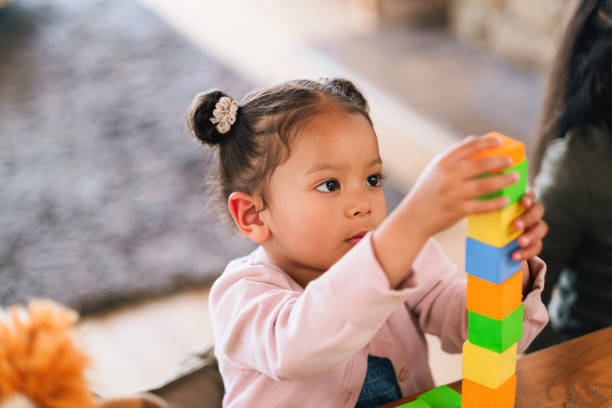 Playing, learning and child with building blocks in home for development, fun and growth. Creativity, puzzle and girl kid with geometric activity for skills and cognitive education with toys in house