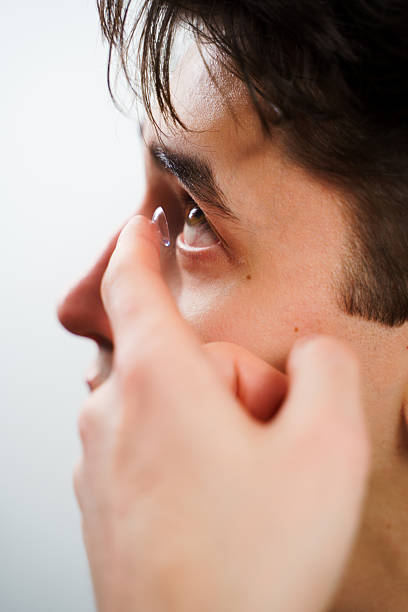 istock Correcting eye wellnesses with optical contact lenses. Man inserts a contact lens into eye for myopia treatment. 2205496688