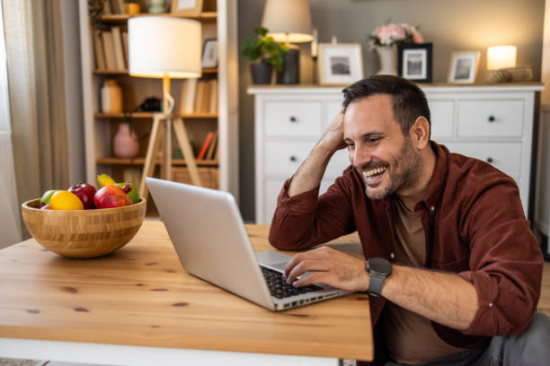 istock Happy man working from home and laughing at laptop 2205497194