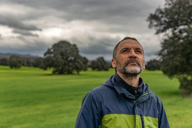 Villamantilla, Madrid, Spain. Worried farmer looking up at the cloudy sky in a green cereal field, hoping for rain or sun
