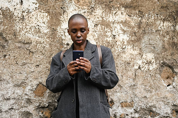 woman browsing social media on her phone while standing against a weathered wall