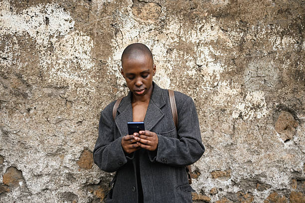 istock Young woman browsing social media on her phone while standing against a weathered wall 2205507786