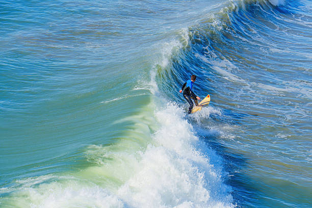 Solana Beach, California, USA-April 17, 2024: Lone surfer riding a frothy wave.