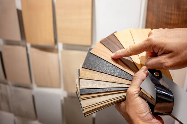 istock Designer hand pointing at sample of wood laminated from natural collection in material showroom. Choosing wooden veneer texture or MDF board swatch fan set for interior finishing or furniture design 2205514622