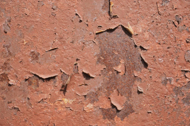 red peeling paint on sheet steel surface under direct sun light - full-frame background and texture