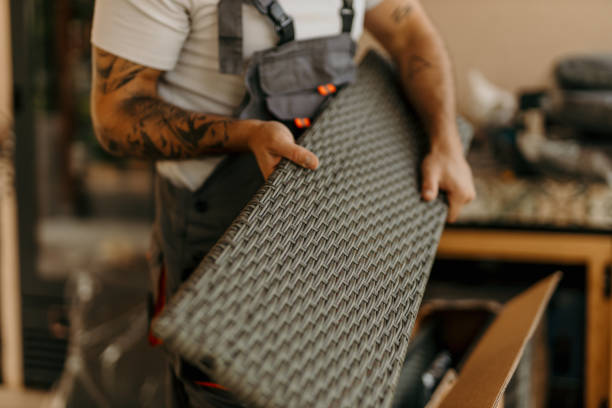 Close-up view of a carpenter's skilled hands working meticulously to assemble a piece of wicker furniture in an outdoor terrace setting