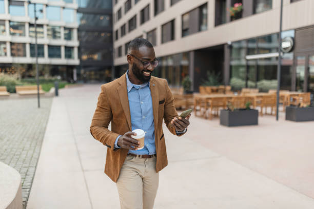 istock Businessman checking phone while walking outdoors 2205517755