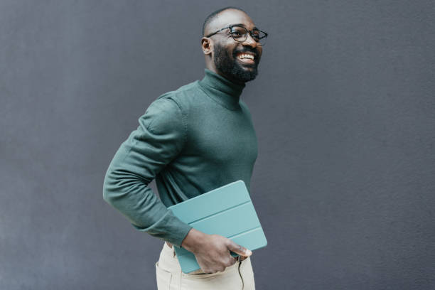 Smiling man in green sweater holding tablet device