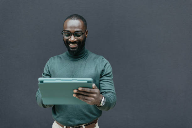 Smiling Man with Tablet Against Dark Background