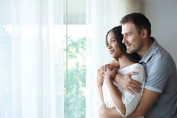 istock Relaxed interracial couple looking through a window 2205518458