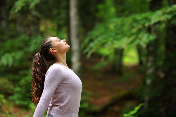 istock Woman breathing fresh air standing in a forest 2205518594