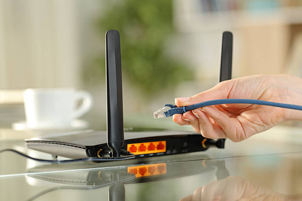 istock Woman hand holding ethernet cable ready to plug in modem 2205518754