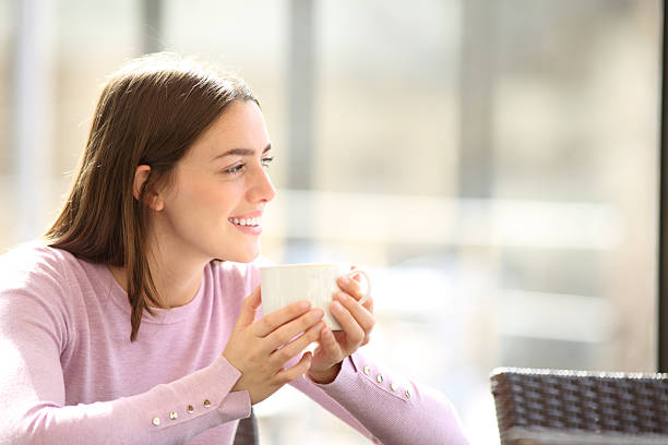 istock Happy woman in a restaurant drinking coffee looking away 2205518929