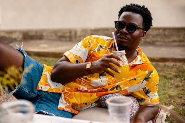 Handsome young black man with sunglasses enjoying juice outdoors on picnic