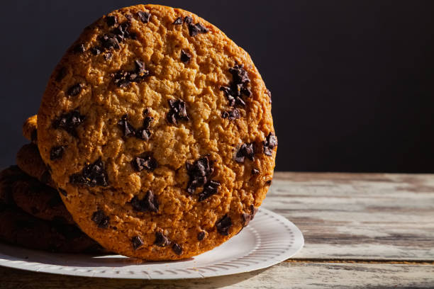 istock Giant cookie on a white plate with disposable tableware. Represents a quick breakfast on the go or in the office. 2205522368