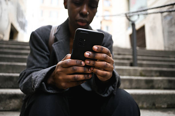 istock Young stylish businesswoman using smartphone sitting on urban steps 2205522732