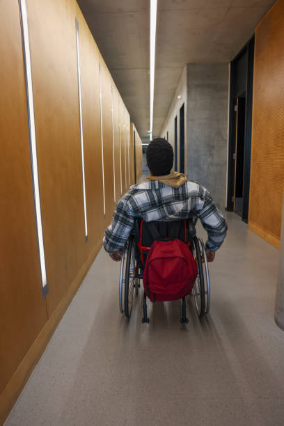 istock Man in wheelchair in office corridor 2205523930