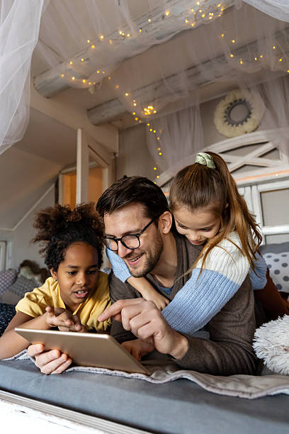 istock Single father playing with his multiethnic, diverse kids on the bed with digital tablet at home 2205524890