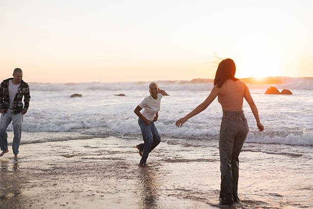 istock Playful friends running in the ocean waves at sunset 2205525710