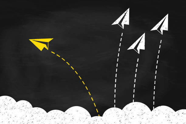 istock Individual and yellow paper plane changing direction around the clouds on black chalkboard 2205526441