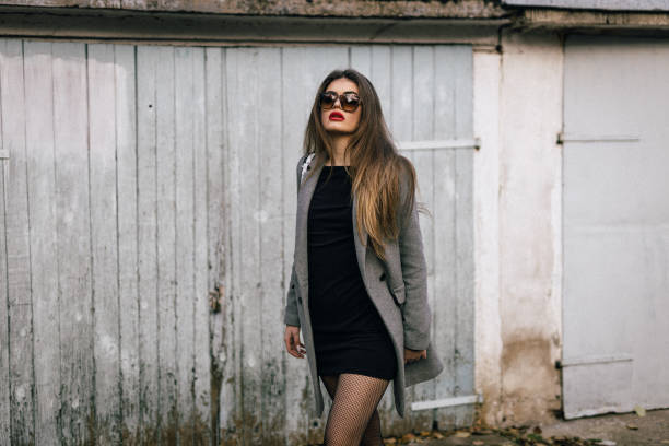 Young woman in a fashionable outfit stands beside an old garage door, capturing the essence of street style and urban chic.nce and street style.t.