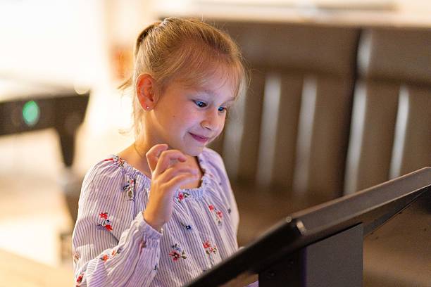 istock Primary school girl using big touch screen display and delighted looking around. Children and modern technology concepts. 2205528778