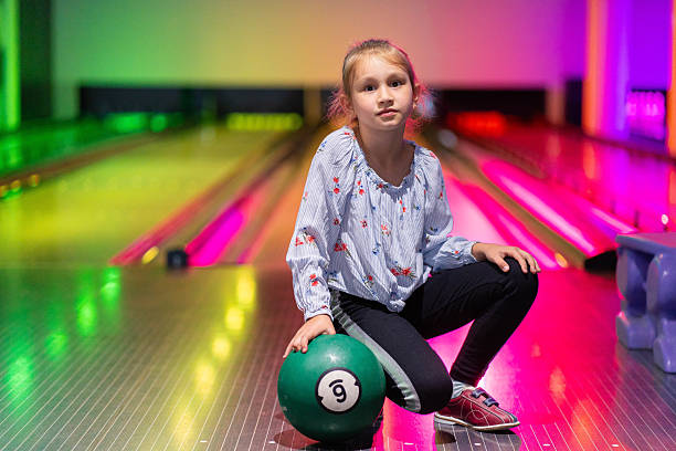istock happy young girl having fun cheering while playing bowling game bowling alley 2205528812