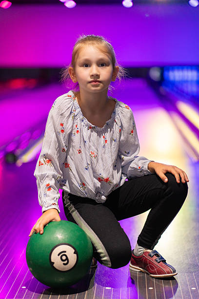 istock happy young girl having fun cheering while playing bowling game bowling alley 2205528822