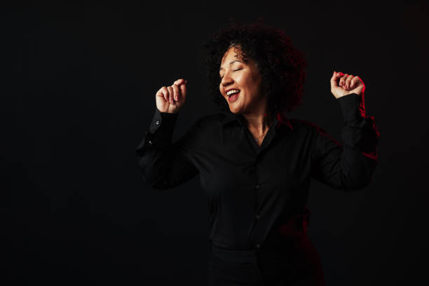 istock Enthusiastic businesswoman dancing and having fun on black background 2205529278