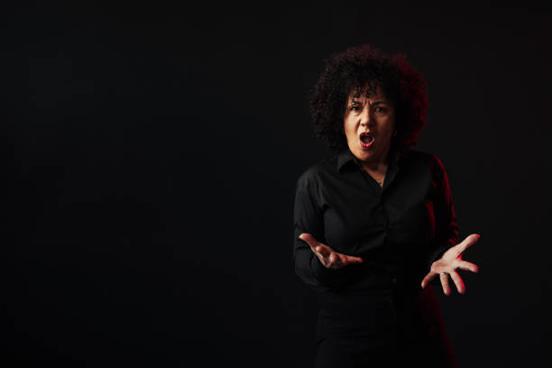 Mature businesswoman wearing black shirt arguing and gesturing with hands on black background