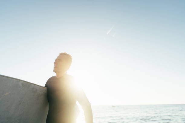istock Senior surfer holding his surfboard 2205530535