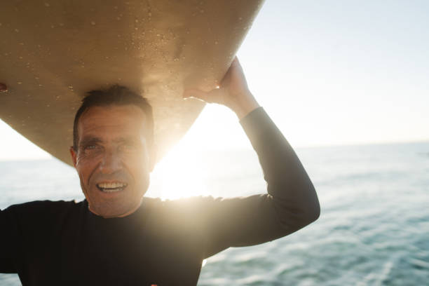 istock Senior surfer holding his surfboard 2205530541