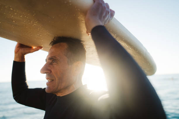 istock Senior surfer holding his surfboard 2205530546