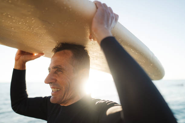 istock Senior surfer holding his surfboard 2205530588