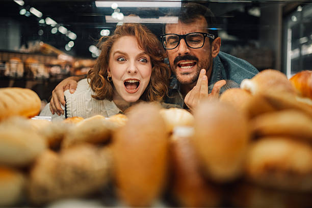 istock Couple admiring fresh bread display in bakery window 2205533171