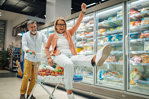 istock Playful senior couple having fun while shopping in supermarket 2205533238