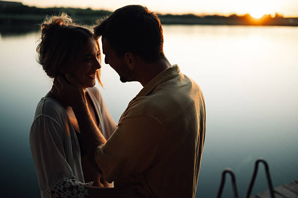 istock Romantic couple embracing by the lake at sunset 2205533825