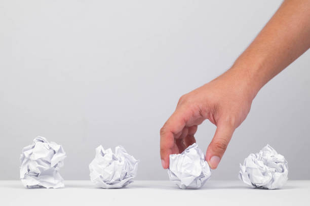 istock A hand picking up a crumpled paper amidst several others on a table, symbolizing ideas or creative processes. 2205534944