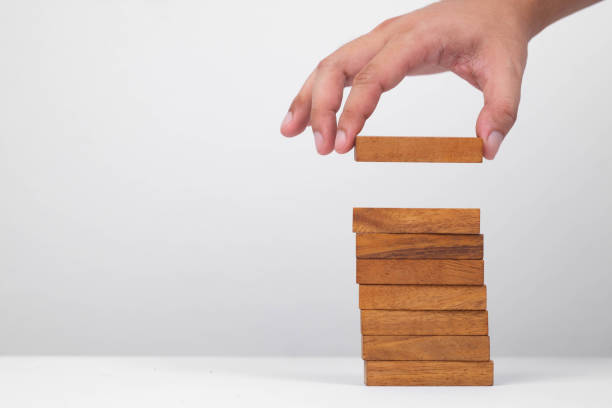 istock A hand placing a wooden block on top of a stack, representing balance, strategy, and construction in play. 2205534956