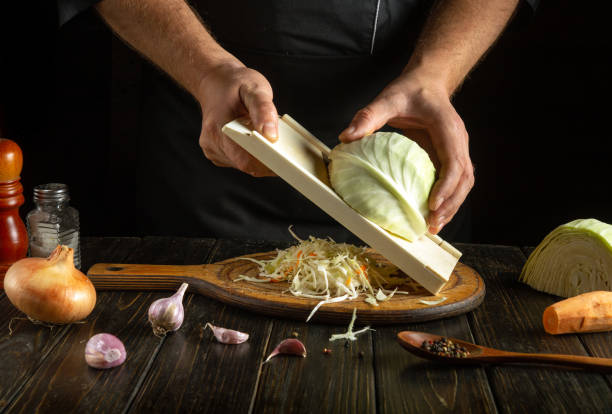 istock In a cozy kitchen, a chef expertly shreds fresh cabbage onto a wooden board, surrounded by colorful vegetables and seasonings, preparing for a delicious salad 2205537352