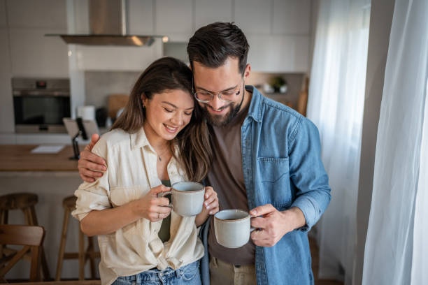 istock Happy couple embracing and drinking coffee in their modern kitchen 2205539785