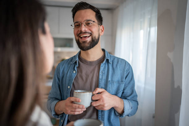 istock Young bearded man smiling and talking to his partner while drinking coffee 2205539832