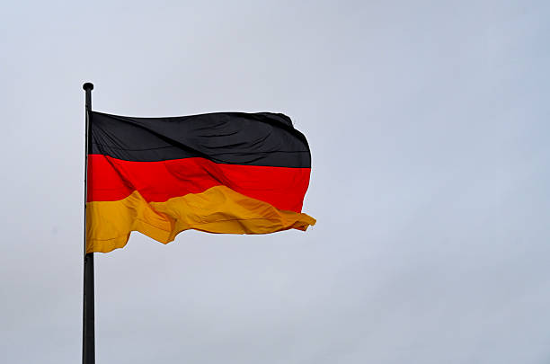 istock Flag of Germany waving against sky on flagpole 2205540116