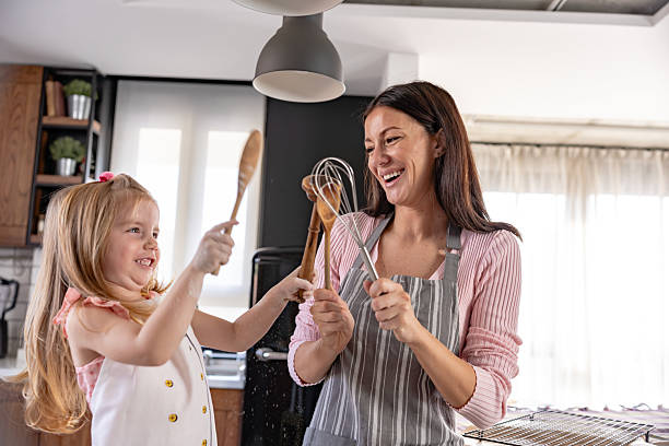 istock A joyful mother and daughter playfully clashing kitchen utensils while cooking together in a modern home kitchen. 2205540813