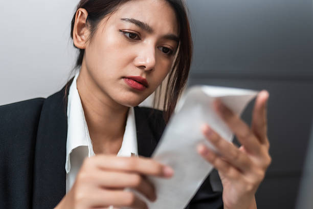istock woman in black suit examines receipt with concerned expression, reflecting on her finances. Her focused demeanor suggests she is analyzing expenses carefully 2205540851