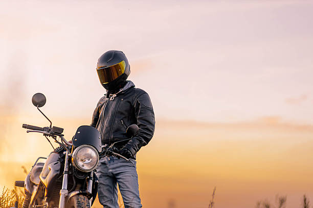 istock motorcyclist in leather jacket at sunset with helmet 2205542997