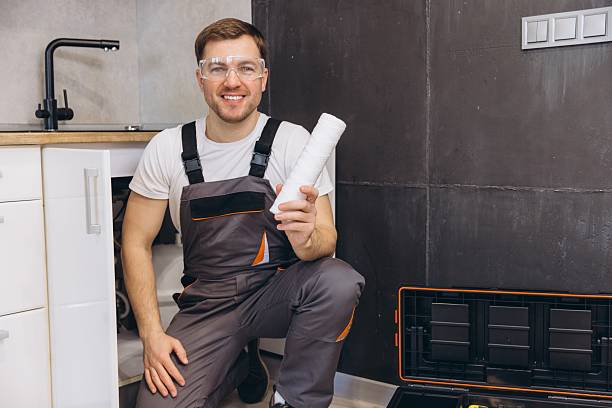 istock Plumber holding water filter cartridge and smiling at kitchen sink 2205544347