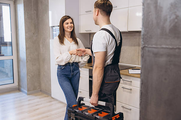 Plumber shaking hands with woman after finishing work in kitchen